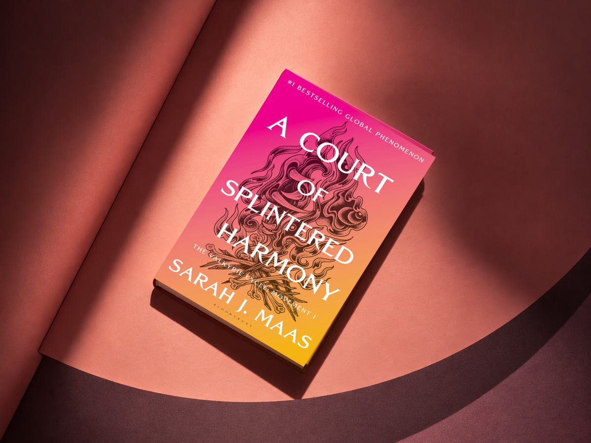A Court of Splintered Harmony hardcover on a dusty rose and plum studio backdrop