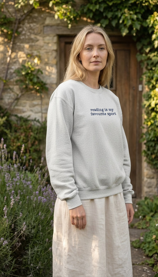 Woman wearing a light gray sweatshirt with text, standing outdoors in a garden.