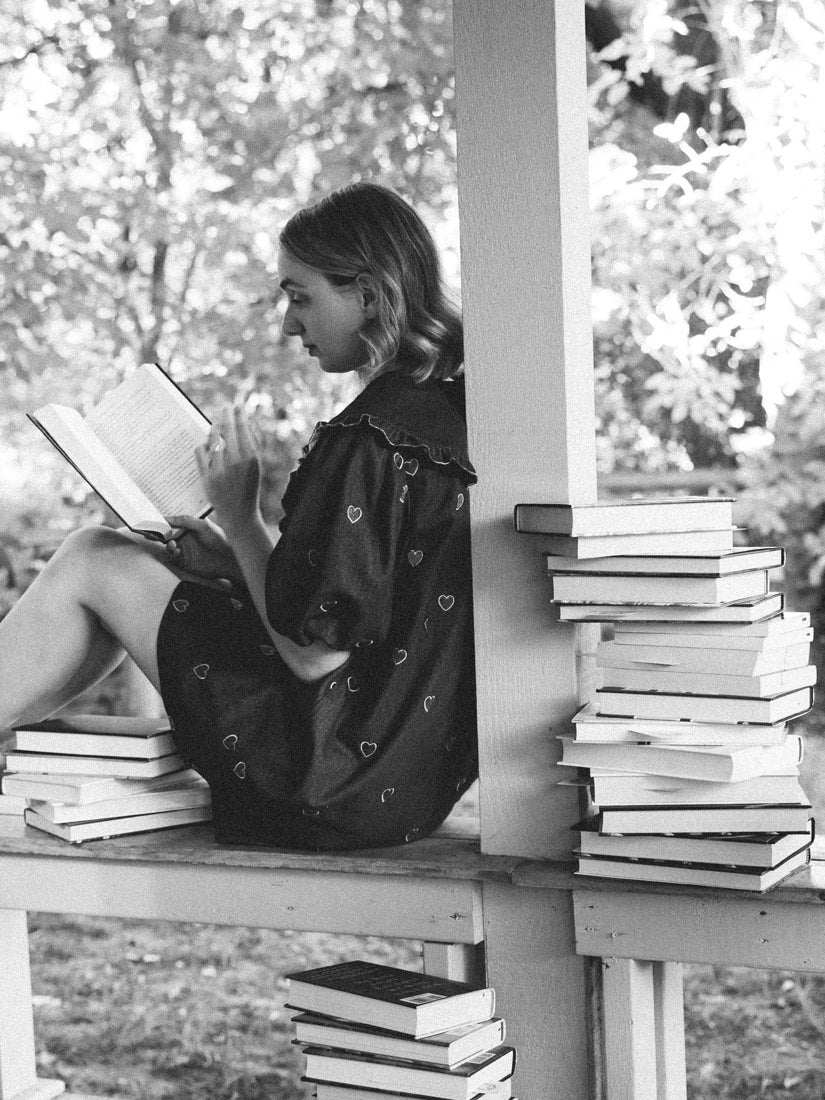 A reader settled in with a stack of books on the porch at Nottawa Cottage Bookstore